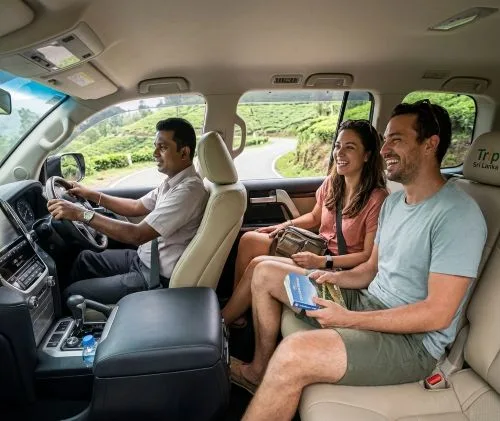 A smiling couple traveling through the Sri Lanka tea country inside a luxury, air-conditioned private chauffeur vehicle.